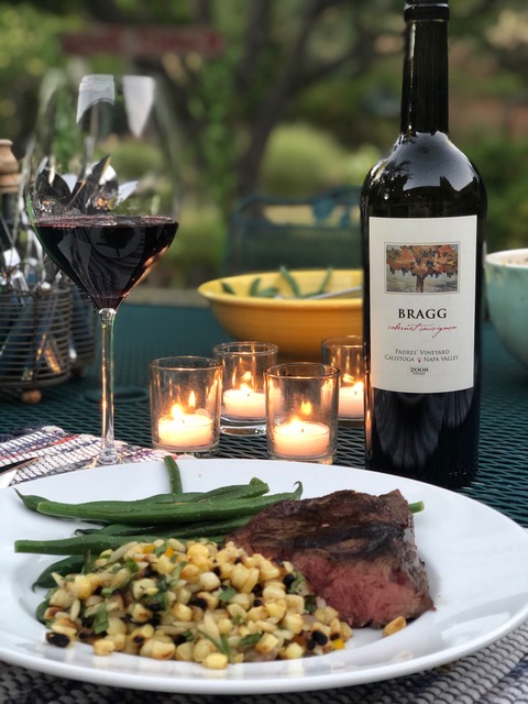 bottle of Bragg Vineyards on a dinner table with a filled glass and a full plate of food